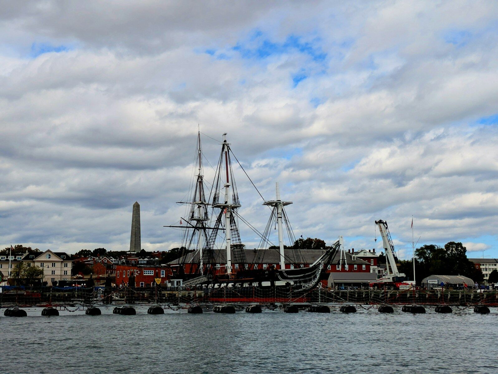 Historic ship docked at a waterfront with monument.