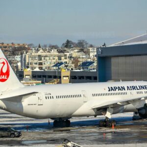 Japan airlines airplane parked on tarmac near hangar.