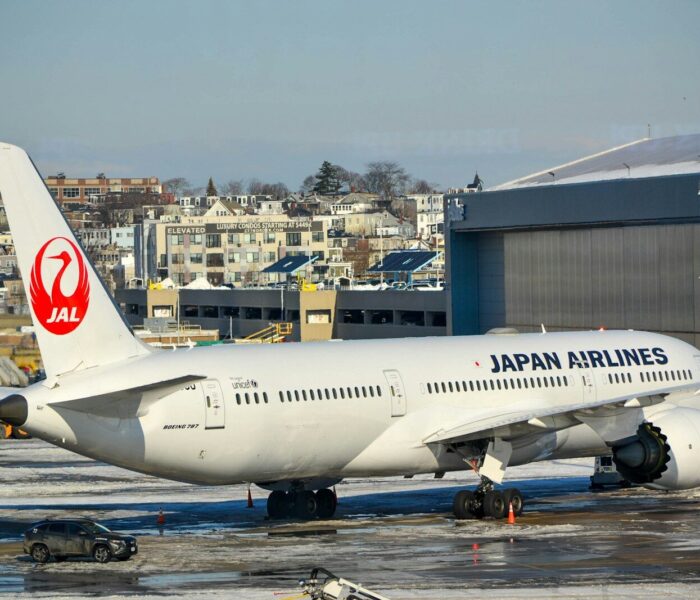 Japan airlines airplane parked on tarmac near hangar.