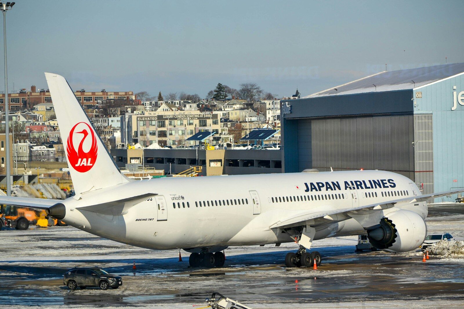 Japan airlines airplane parked on tarmac near hangar.